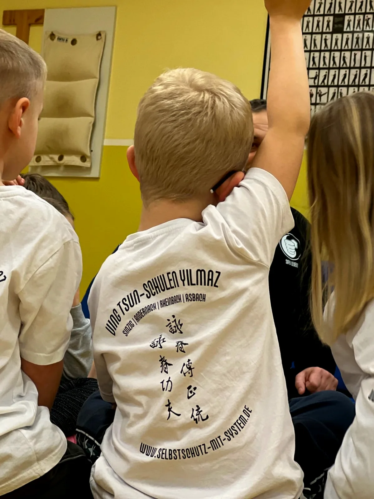 Kinder in Vereins-Shirts strecken im Training die Hände nach oben