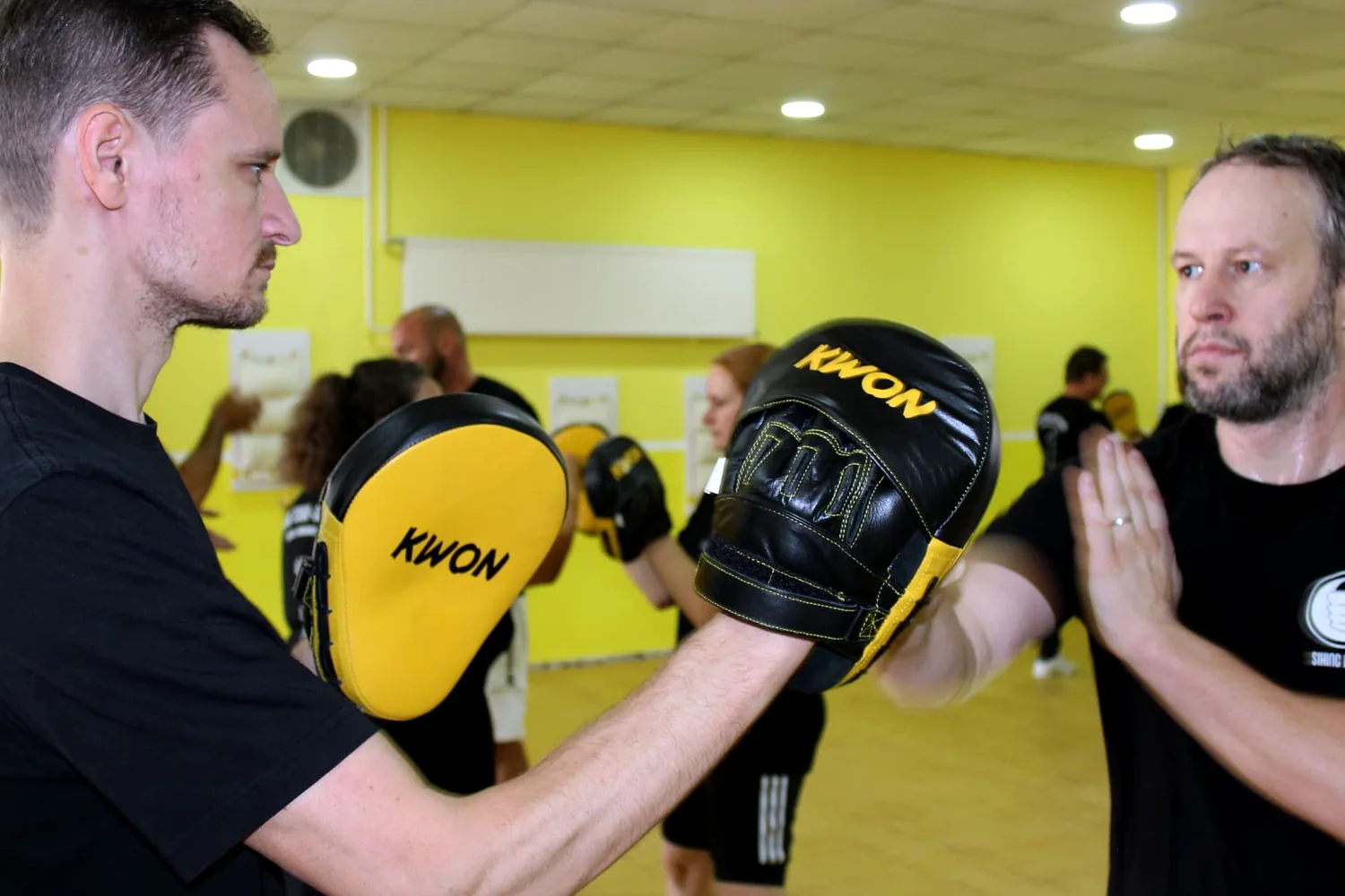 Zwei Erwachsene trainieren mit Pratzen und Handschuhen im Kurs