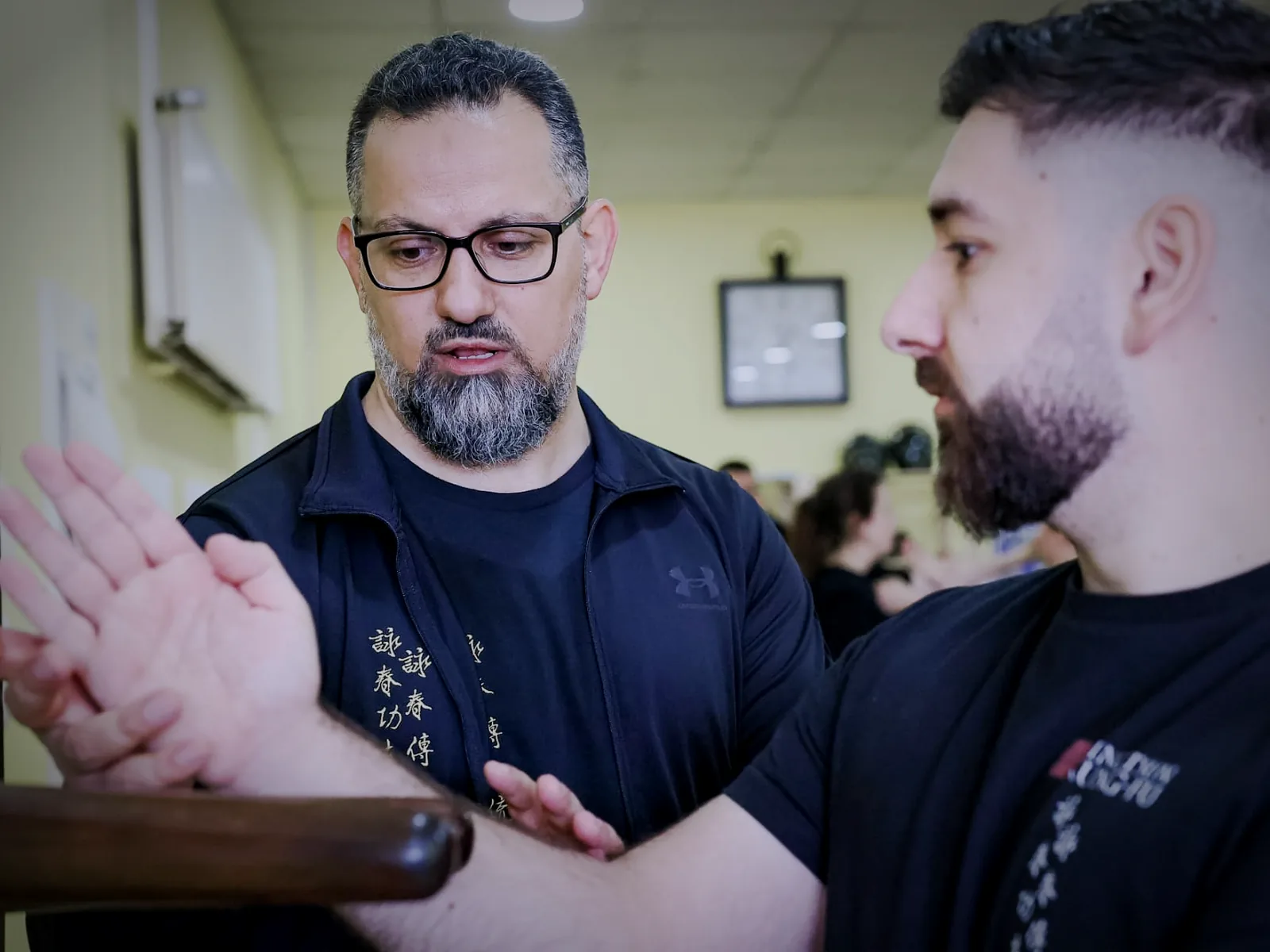 Sifu Levent Yilmaz korrigiert die Armhaltung eines Trainierenden an der Holzpuppe