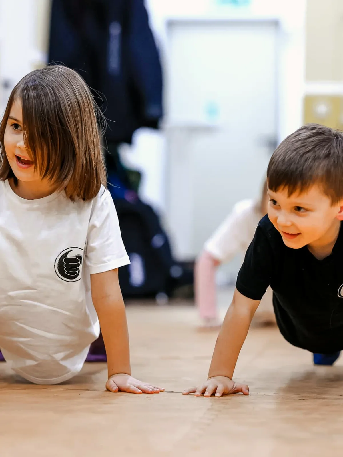 Zwei Kinder machen gemeinsam Liegestütze und lachen sich an