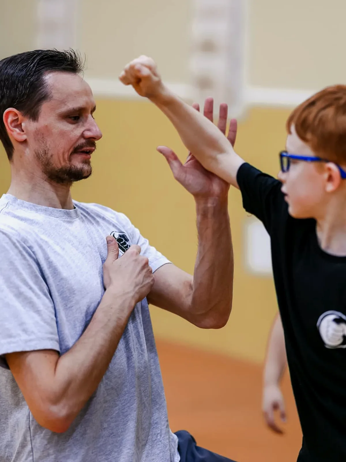 Trainer korrigiert mit einem Jungen eine Abwehrbewegung