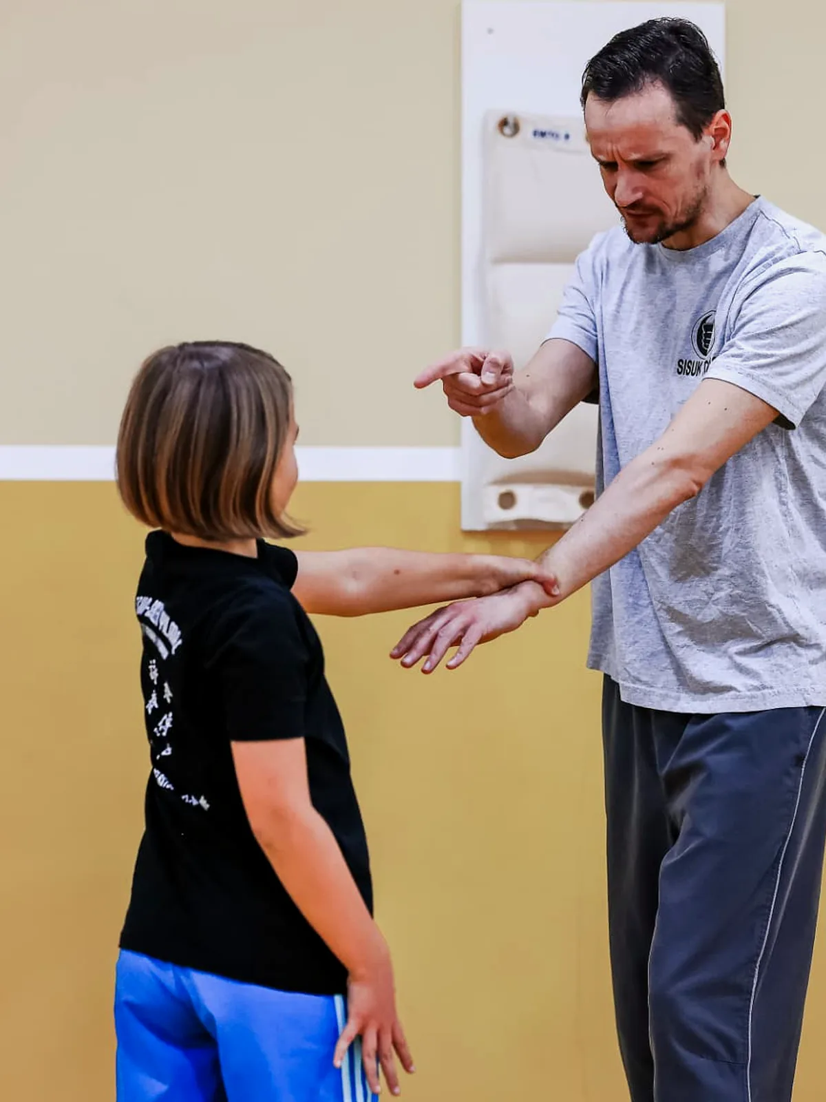 Trainer erklärt einem Kind die Armhaltung