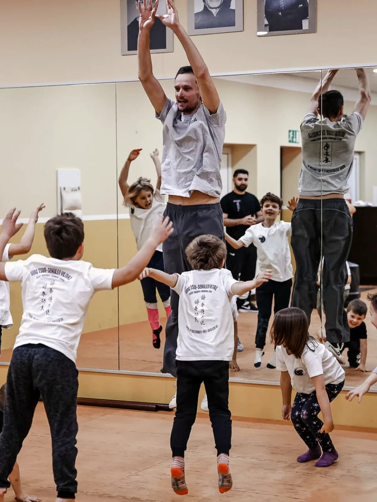 Trainer springt mit der Kindergruppe im Aufwärmspiel in die Luft