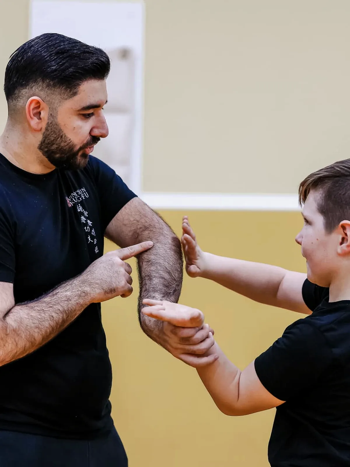Trainer zeigt einem Jungen die Armposition in der Partnerübung